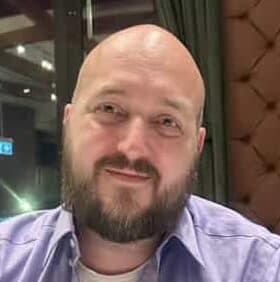 Modern man with a beard and bald head smiling at a restaurant, showcasing a friendly and professional appearance, ideal for digital marketing or client service branding.
