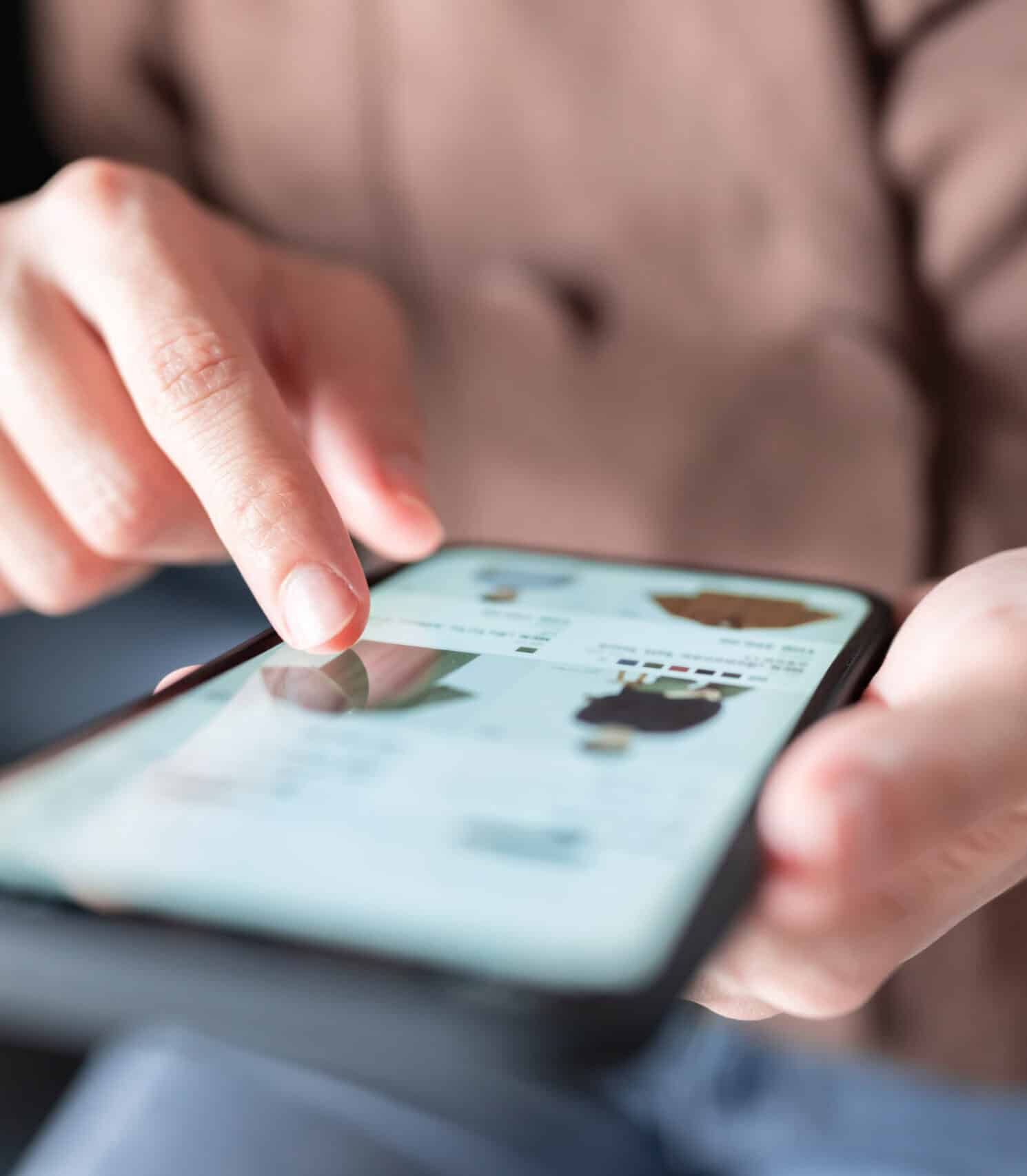 Online shopping on a smartphone, browsing fashion products on an ecommerce site, mobile commerce, digital retail, fashion store app, digital shopping experience.